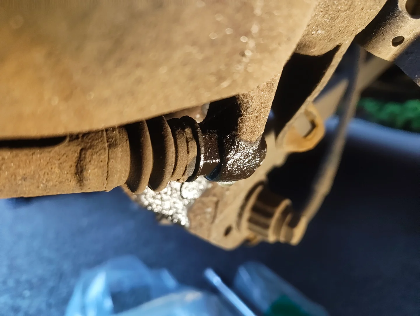 Spraying penetrant on the bottom brake caliper slider pin fixing bolt.