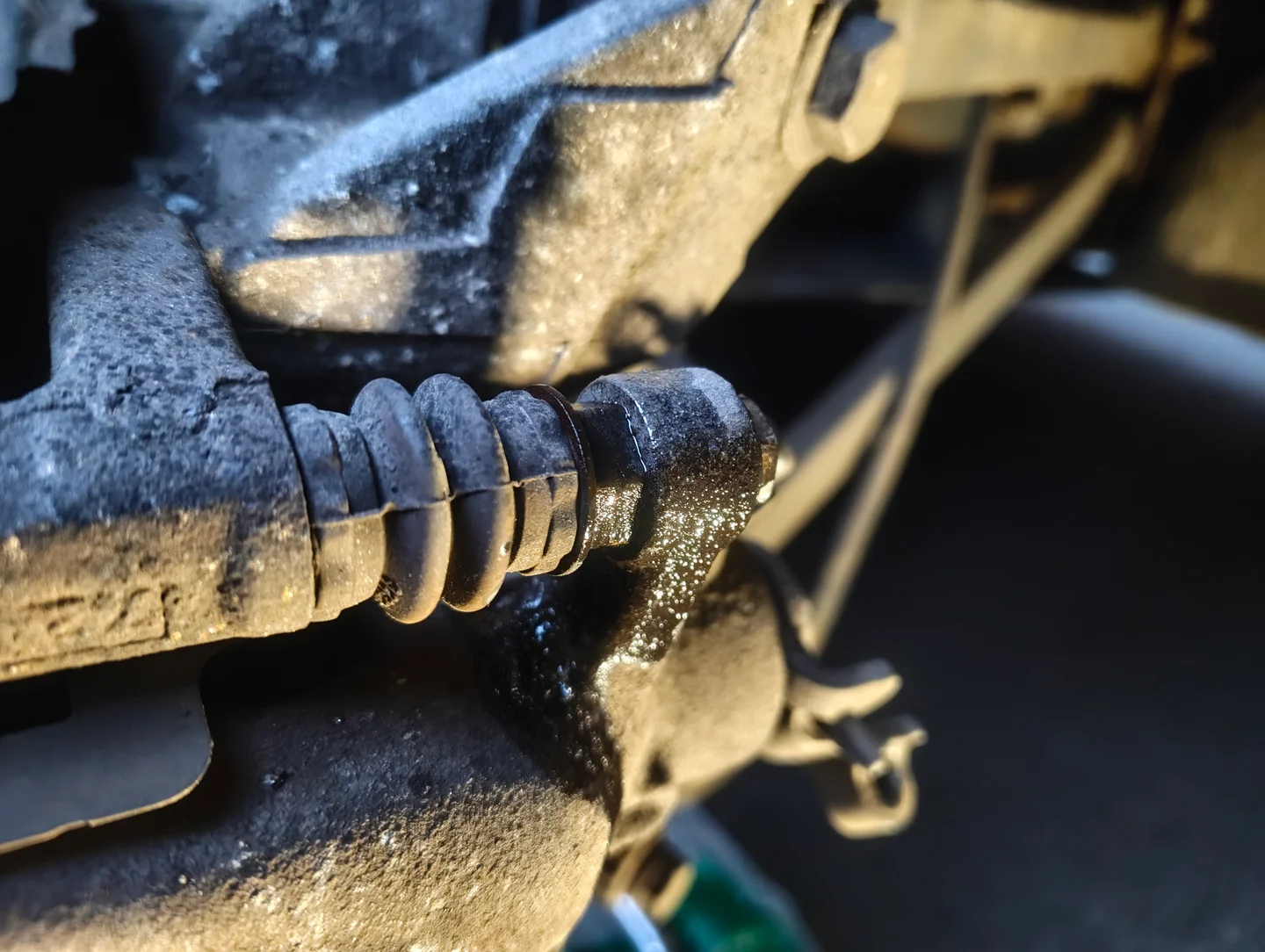 Spraying penetrant on the top brake caliper slider pin fixing bolt.