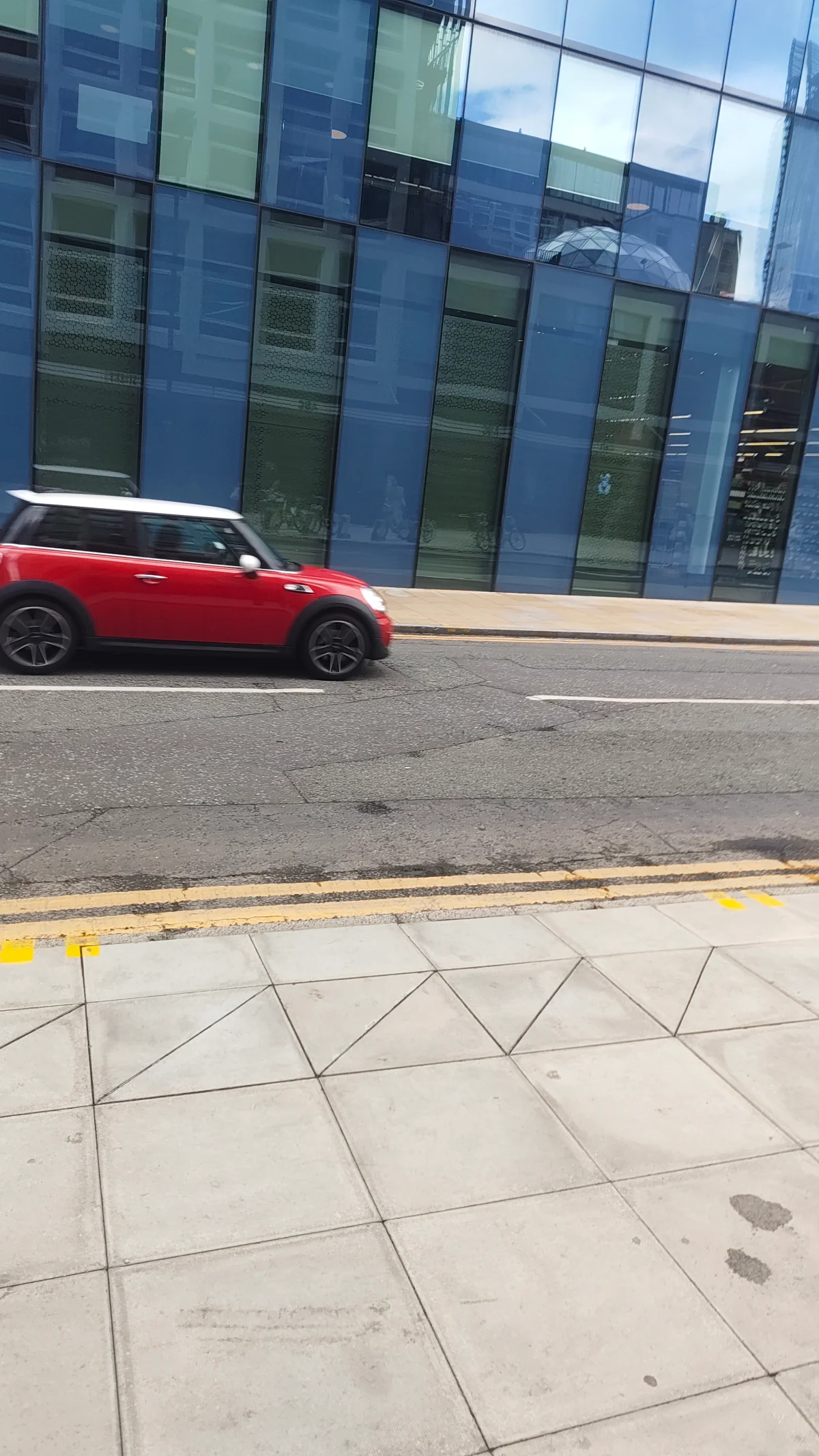 Red MINI R56 passing a glass-fronted building